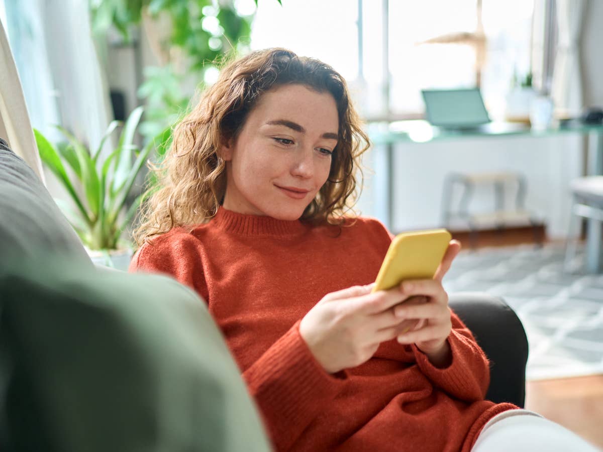 person-sitzt-mit-ihrem-smartphone-auf-der-couch Person sitzt mit ihrem Smartphone auf der Couch