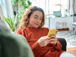 Person sitzt mit ihrem Smartphone auf der Couch