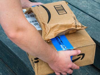Person stellt Amazon-Pakete vor der Haustür ab