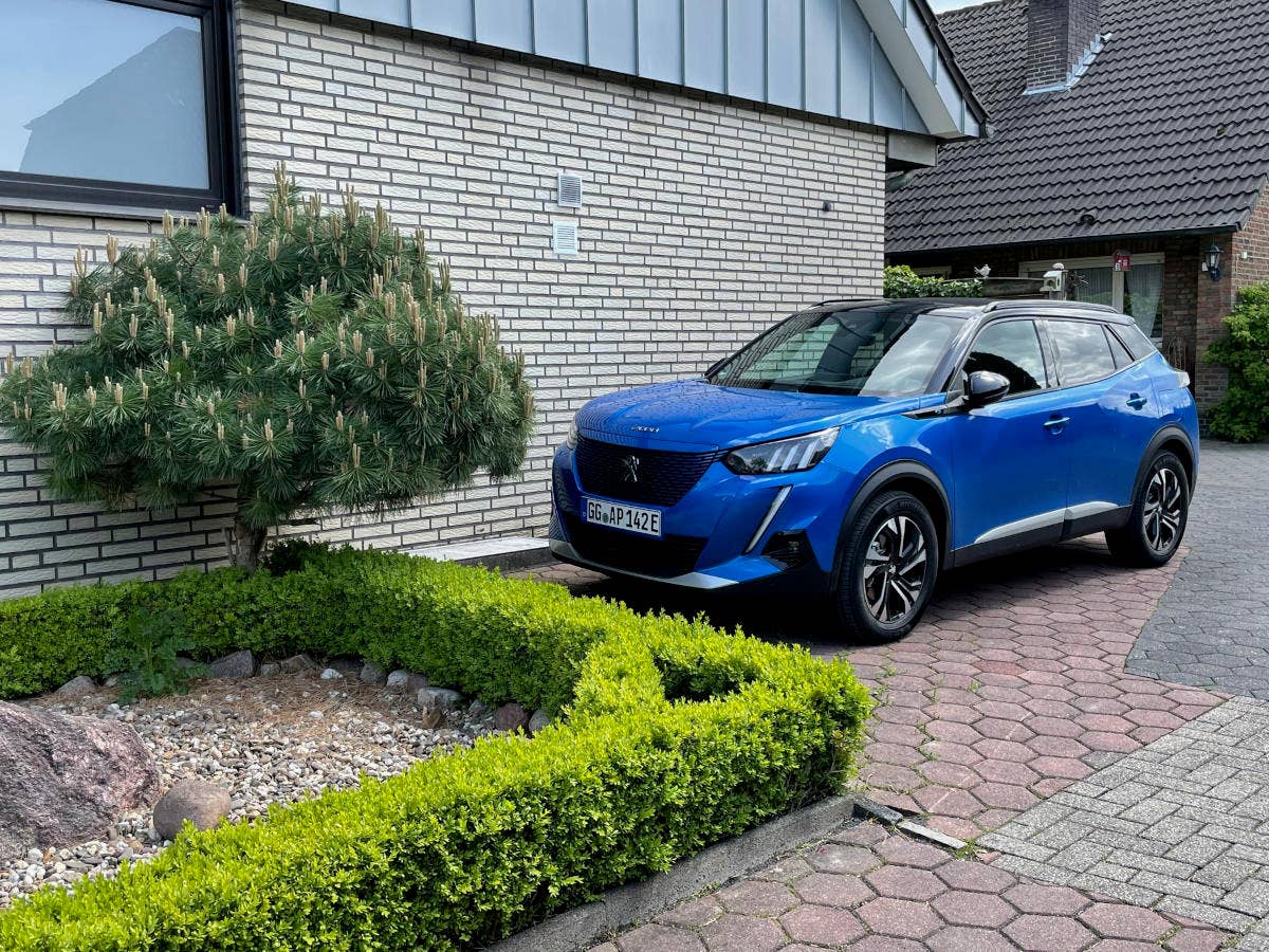 Peugeot e-2008 Peugeot e-2008 steht vor einem Haus.
