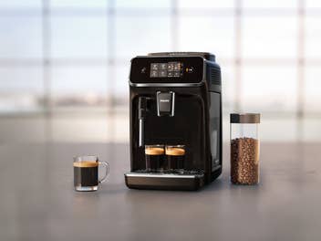 Philips Kaffeevollautomat mit zubereitetem Kaffee und Kaffeebohnen in einem Glas.