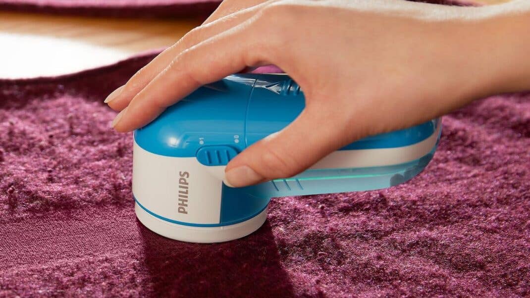 Eine Hand benutzt den Philips Fusselrasierer und entfernt Knötchen von einem Kleidungsstück