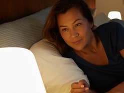 Frau im Bett schaut auf eine smarte Lampe