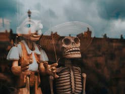 Pinocchio-Figur in Schaufenster neben Skelett.
