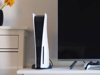 PlayStation 5 neben einem Fernseher auf einer TV-Kommode