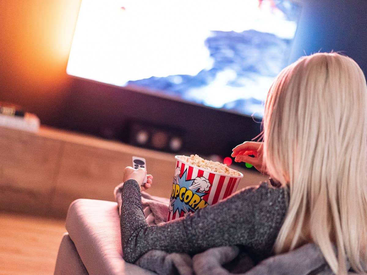 Eine Frau sitzt mit Popcorn vorm TV