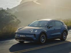 Porsche Cayenne S Electric (2026) fährt auf einer Straße im Sonnenlicht.