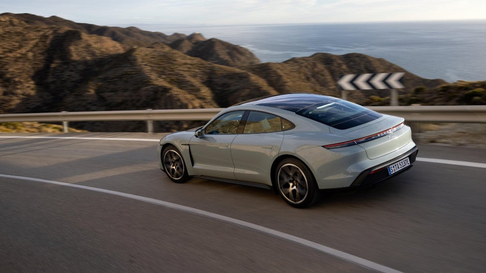 Porsche Taycan auf einer Küstenstraße während der Fahrt.