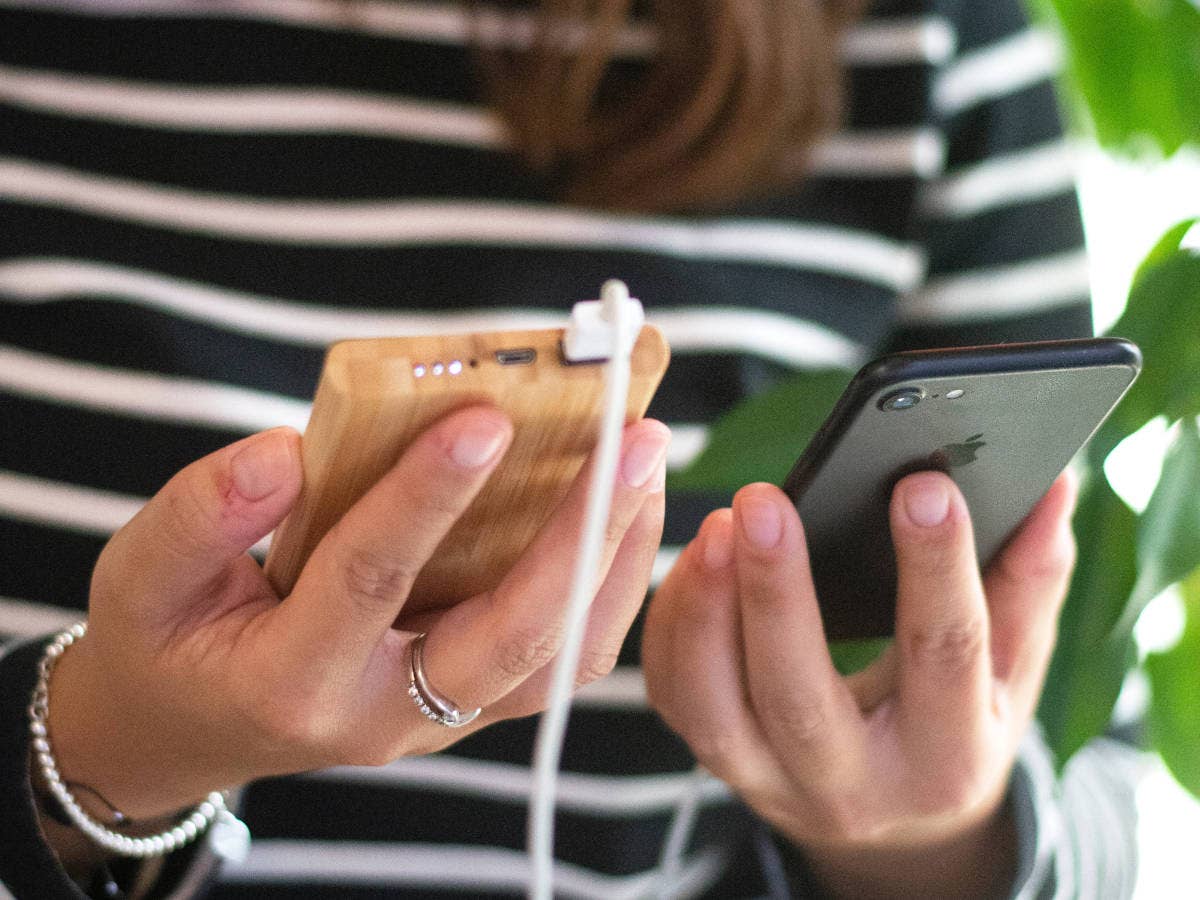 Frau hält eine Powerbank und ein Smartphone in den Händen.