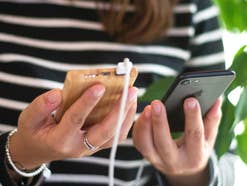 Beste Powerbank kaufen: Stiftung Warentest deckt fiese Falle auf Frau hält eine Powerbank und ein Smartphone in den Händen.