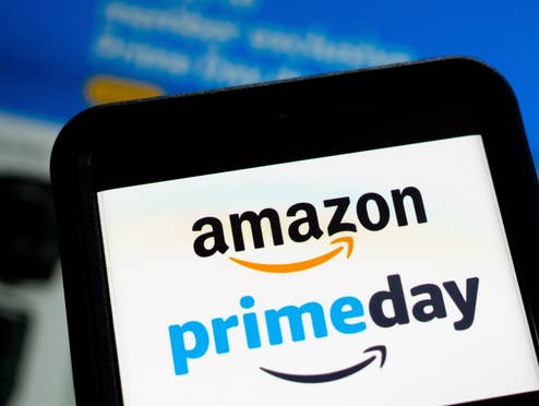 Das Amazon prime day Logo auf einem Smartphone vor einem Bildschirm, auf dem Amazon die Webseite geöffnet ist.