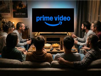 Mehrere Menschen sitzen auf einem Sofa in einer Wohnung und schauen auf einen Fernseher, auf dem das Prime Video Logo zu sehen ist.
