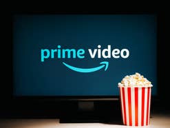 Prime Video Logo auf einem Fernseher mit davor stehender Popcorn-Tüte.