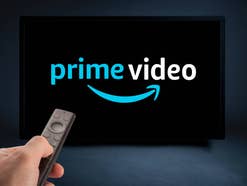 Hand schaltet auf einer Fernbedienung Prime Video von Amazon ein.
