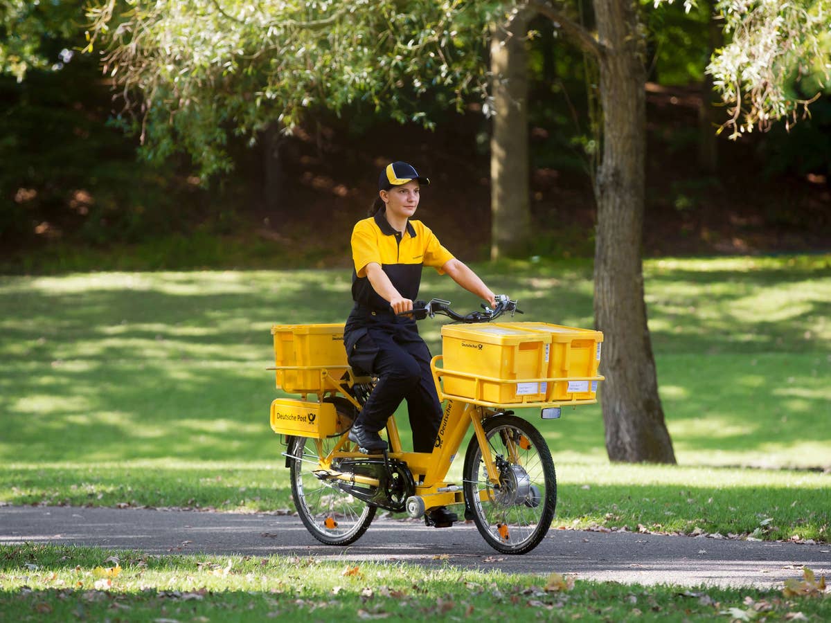 Eine Briefträgerin bei der Zustellung von Post mit dem Fahrrad