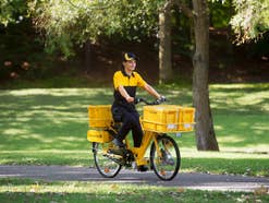 Eine Briefträgerin bei der Zustellung von Post mit dem Fahrrad