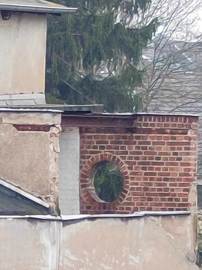 Ein rundes Fenster aus Backsteinen ganz nah mit der Kamera herangezoomt.