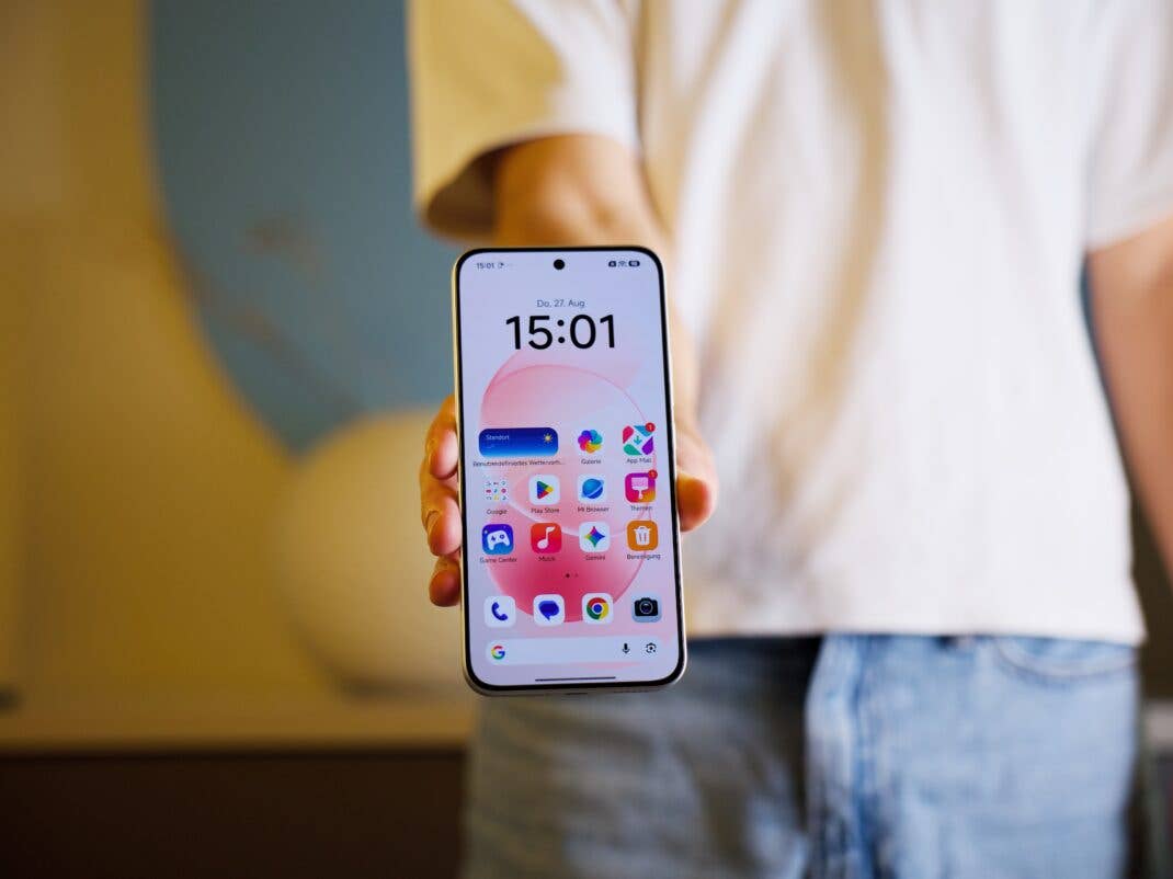Eine Person hält ein weißes REDMI Note 17 Pro Max mit eingeschaltetem Display, auf dem der Startbildschirm mit App-Icons zu sehen ist.