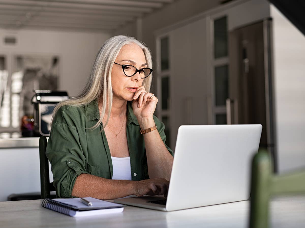 Reife Frau sitzt am Laptop und macht ein besorgtes, nachdenkliches Gesicht