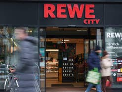 Rewe City-Geschäft, Kunden laufen davor (verschwommen zu sehen)