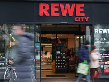 Rewe City-Geschäft, Kunden laufen davor (verschwommen zu sehen)