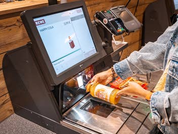 Frau bezahlt an einer Rewe-Kasse