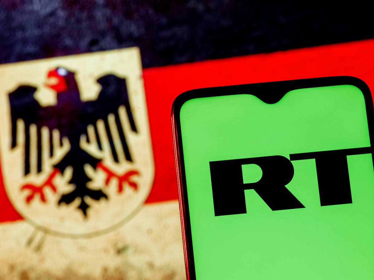Handy mit RT Logo vor deutscher Flagge.