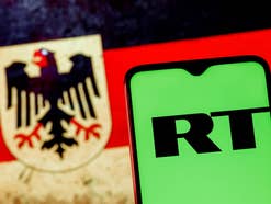 Handy mit RT Logo vor deutscher Flagge.