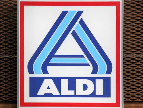 Aldi Logo vor einem verrosteten Gitter.