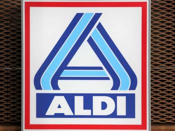 Aldi Logo vor einem verrosteten Gitter.
