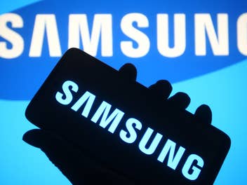 Samsung Logo auf einem Smartphone vor einem Samsung Logo im Hintergrund.