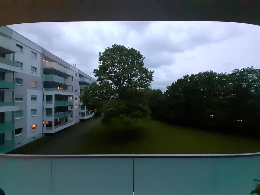 Weitwinkelbild der Wohnsiedlung mit Baum in der Mitte bei Dämmerung