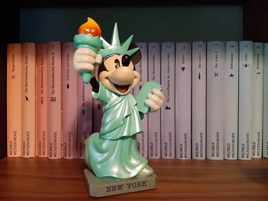 Auch dieses Bild ist im Innenraum aufgenommen. Dieses Foto zeigt eine Mini-Maus-Figur im Regal.