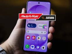 Samsung Galaxy S26 in einer Hand, davor das MediaMarkt-Logo