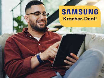 Mann sitzt auf einem Sofa und bedient ein Tablet