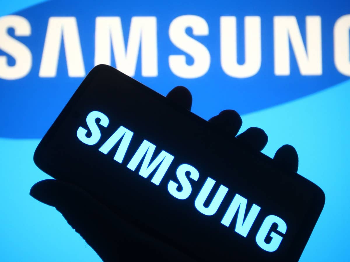 Samsung Smartphone mit Samsung-Logo Samsung-Logo auf einem Smartphone, im Hintergrund das Samsung-Logo auf einer blauen Wand