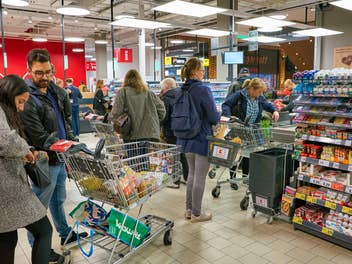 Mehrere Kassen im Supermarkt und Kunden, die anstehen