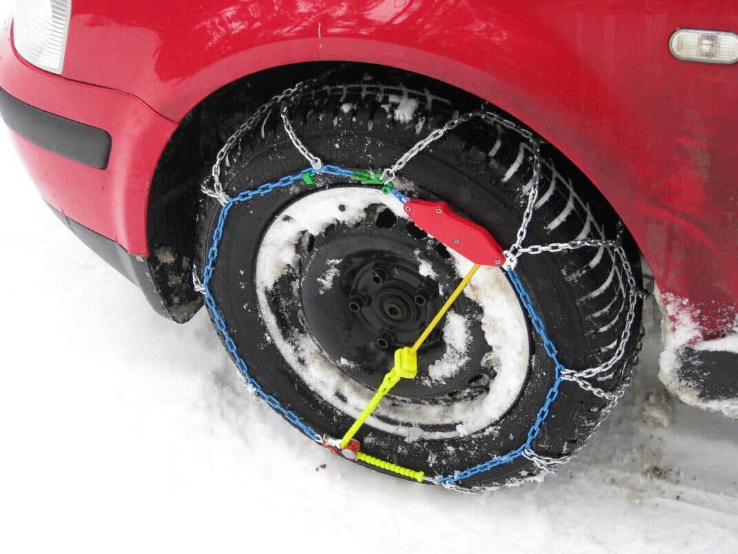 Ein rotes Auto fährt mit Schneeketten