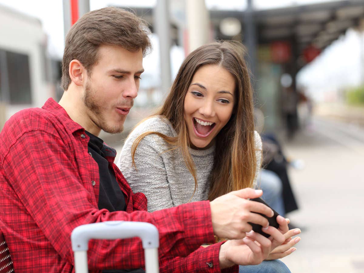 Mann und Frau spielen an einem Bahnhof ein Smartphone-Spiel.
