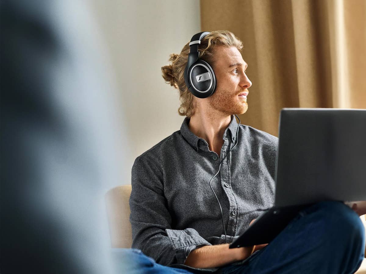 Mann trägt die Sennheiser HD 599 Special Edition und hat einen Laptop auf dem Schoß.