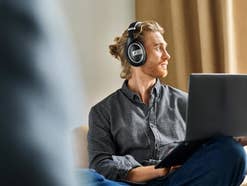 Mann trägt die Sennheiser HD 599 Special Edition und hat einen Laptop auf dem Schoß.