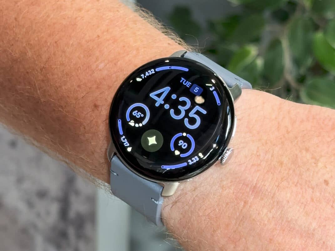 Eine Google Pixel Watch 4 zeigt die Uhrzeit 4:35 und verschiedene Gesundheitsdaten am Handgelenk an.
