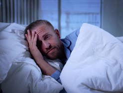 Ein Mann liegt verzweifelt in seinem Bett