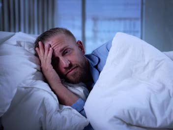 Ein Mann liegt verzweifelt in seinem Bett