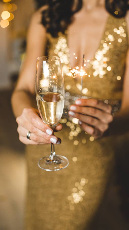 Eine in gold gekleidete Frau mit einem Sektglas in der Hand