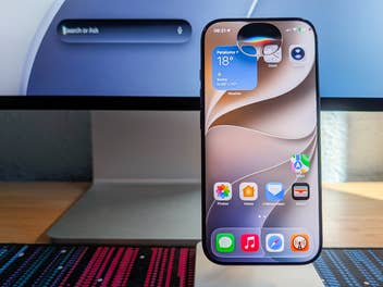 Neue Siri-Oberfläche auf einem iPhone vor einem Mac mit schwebendem Siri-Suchfeld