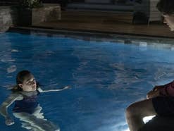 Eine Frau schwimmt im Pool und sieht einen Mann an, der am Rand sitzt