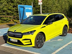 Skoda Enyaq RS iV steht an einer Ladesäule im Sonnenlicht.