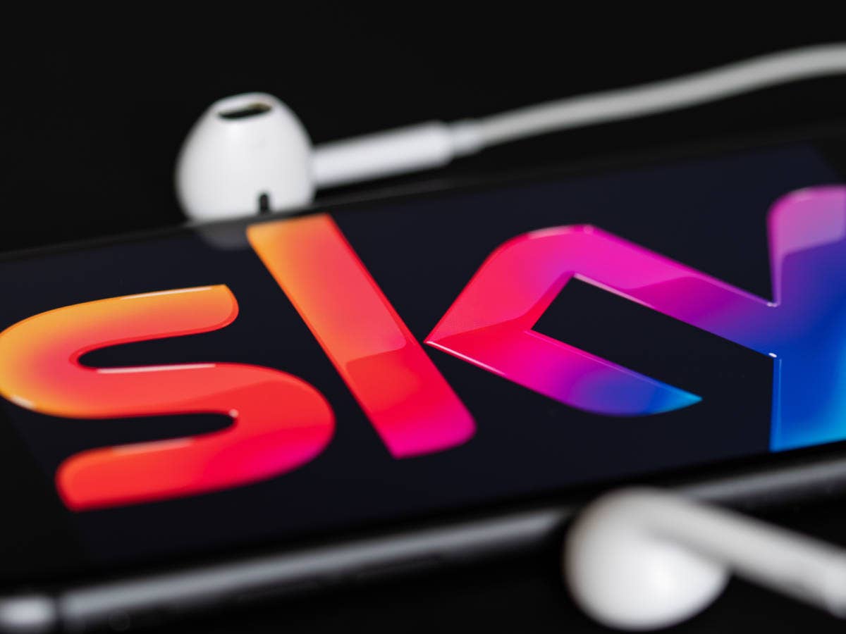 Sky-Logo auf einem Smartphone mit angeschlossenen Kopfhörern.
