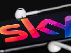 Sky-Logo auf einem Smartphone mit angeschlossenen Kopfhörern.